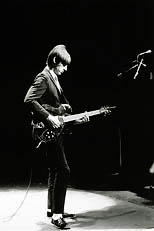 thumbnail link to close-up photograph Paul Weller tuning guitar on stage