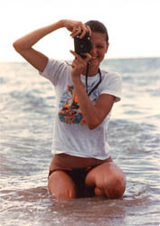 Barbara McQueen kneeling in surf with camera