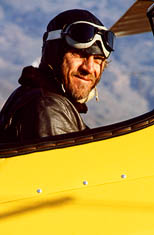 thumbnail link to photograph of Steves miling in cockpit, leather flying helmet